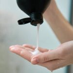 Pouring shampoo from bottle on female hand in bathroom. Hygiene concept