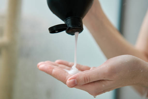 Pouring shampoo from bottle on female hand in bathroom. Hygiene concept