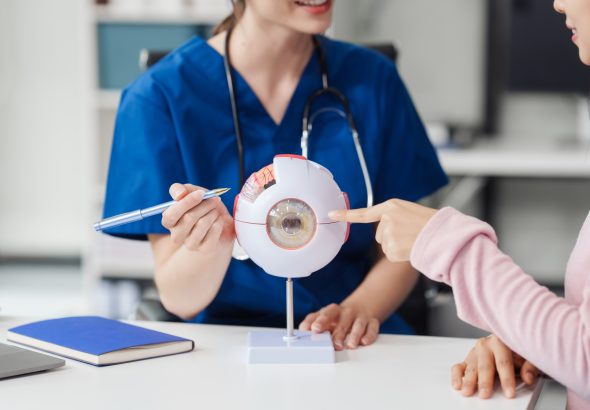 Female Caucasian ophthalmologist explains about eye diseases using the eye model with an Asian female patient At the table in the hospital examination room, Glaucoma, Cataract, Diabetic Retinopathy